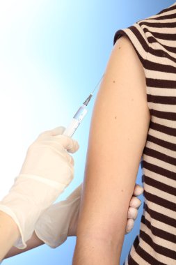 Doktor holding şırınga ile hasta omzundan, mavi zemin üzerine aşı