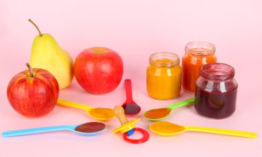 kaşık ile meme ve pembe bir arka plan üzerinde meyve içinde bebek püresi