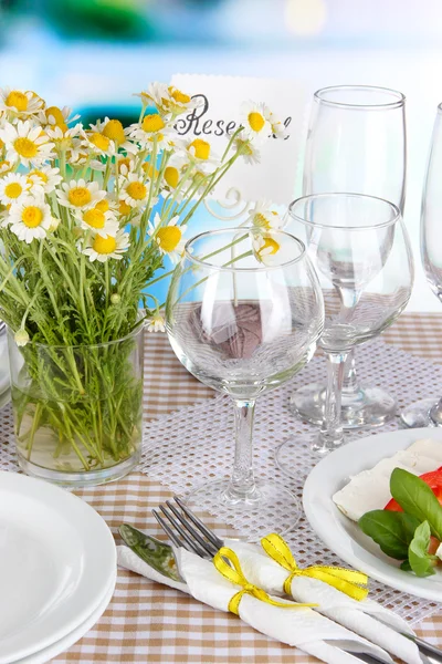 Table setting with chamomiles on checkered tablecloth on window background — Stock Photo, Image