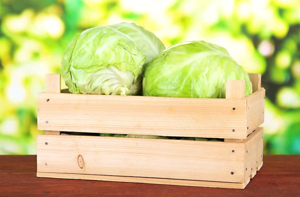 Green cabbage in wooden box, on bright background — Stock Photo, Image