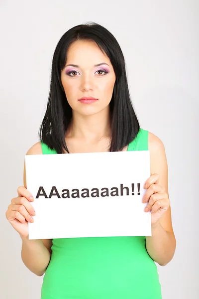 Mujer joven sorprendida lleva la inscripción "ah" sobre fondo gris — Foto de Stock