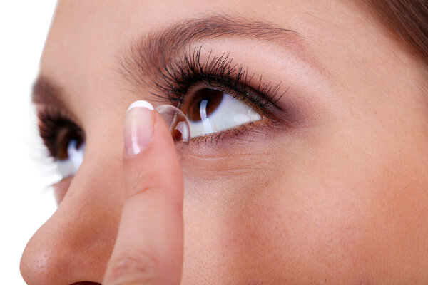 Young woman putting contact lens in her eye close up