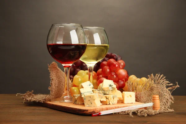 Композиция с вином, голубым сыром и виноградом на деревянном столе, на сером фоне — стоковое фото