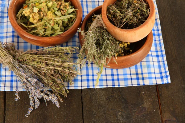 Medicinalväxter i trä skålar på servett på träbord — Stockfoto