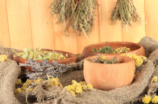 Herbes médicinales dans des bols en bois sur l'ensachage sur la table sur fond en bois — Photo