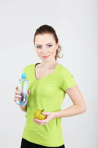 Belle jeune femme avec bouteille d'eau et pomme — Photo