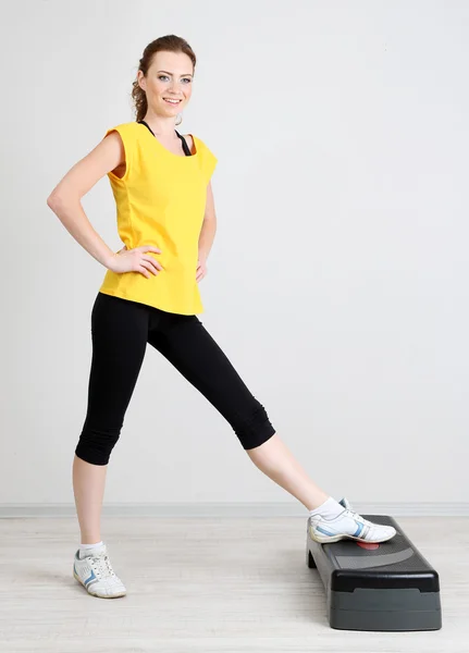 Beautiful young woman exercises on stepper — Stock Photo, Image