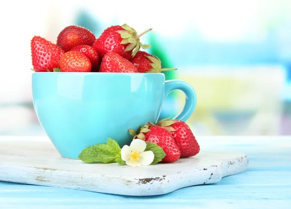 青い木製のテーブルの上にカップに熟した甘いイチゴ — ストック写真