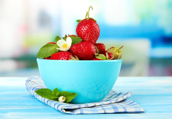 Ripe sweet strawberries in bowl on blue wooden table — Stock Photo, Image
