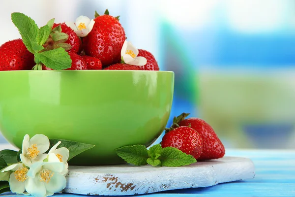 Reife süße Erdbeeren in grüner Schüssel auf blauem Holztisch — Stockfoto