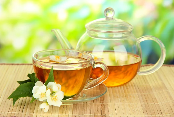 Cup of tea with jasmine, on bamboo mat, on bright background — Stock Photo, Image