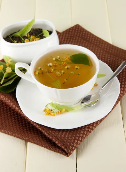 Cup of tea with linden on napkin on wooden table — Stock Photo, Image