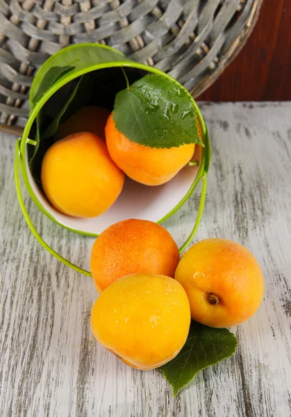 Apricots in bucket on wooden table near wicker coasters — Stock Photo, Image