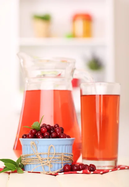 Pitcher and glass of cranberry juice with red cranberries on table — Stock Photo, Image