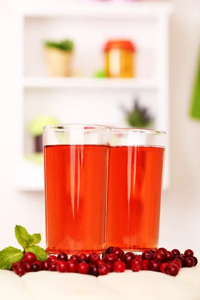 Стаканы клюквенного сока и спелые красные клюквы на столе — стоковое фото