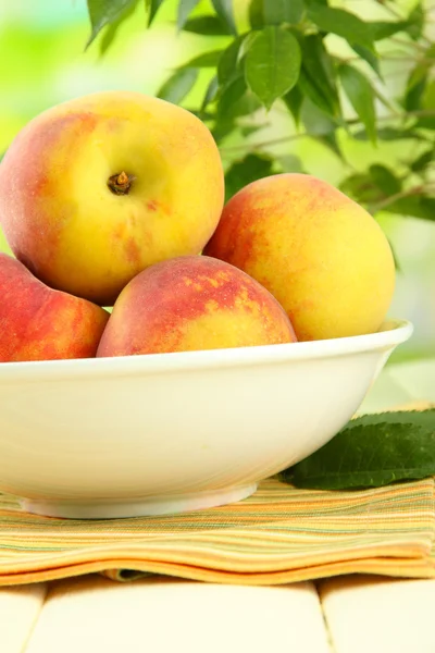 Ripe sweet peaches on table in bowl, outdoors — Stock Photo, Image