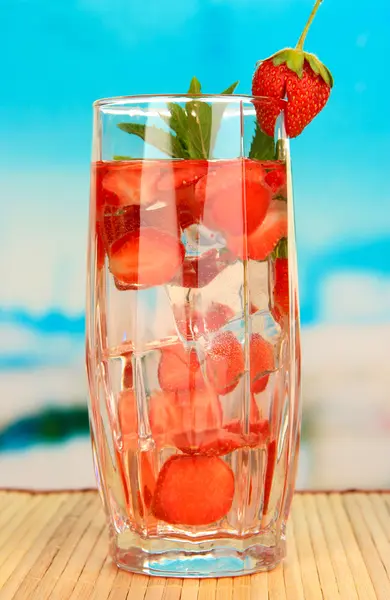 Verre de boisson aux fruits avec glaçons sur fond bleu — Photo