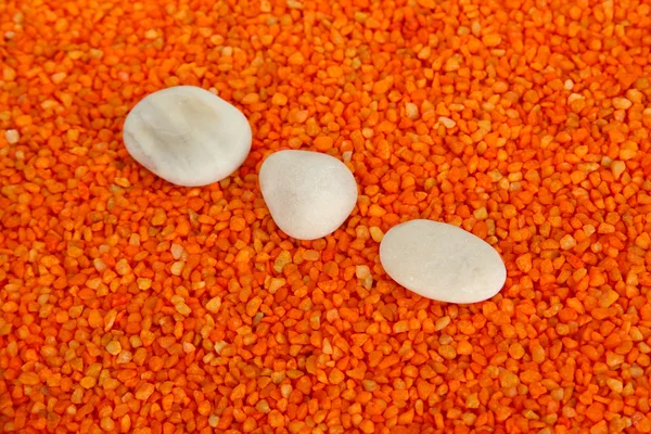 White stones on orange crystals of sea salt background — Stock Photo, Image