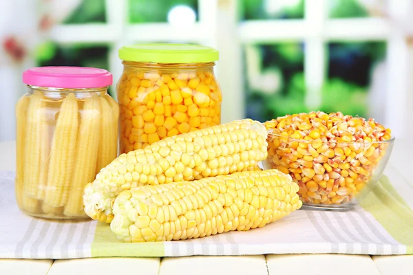 Fresh, canned and dried corn on wooden table, on bright background — Stock Photo, Image