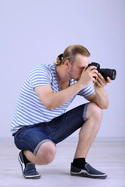 Fotógrafo guapo con cámara, sobre fondo gris — Foto de Stock