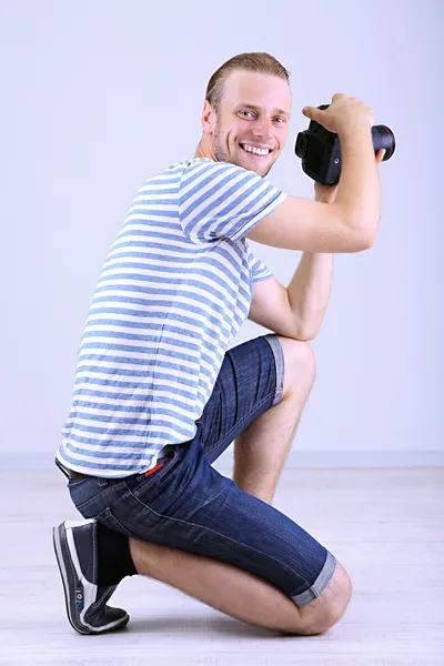 Handsome photographer with camera, on gray background — Stock Photo, Image