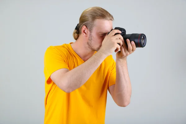 Pěkný fotograf s kamerou, na šedém pozadí — Stock fotografie