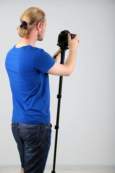 Fotógrafo guapo con cámara en monopode, sobre fondo gris —  Fotos de Stock