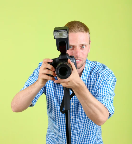Handsome photographer with camera on monopod, on green background — Stock Photo, Image