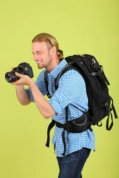 Knappe fotograaf met camera, op groene achtergrond — Stockfoto