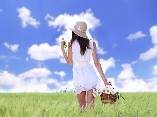 Retrato de una hermosa joven con flores en el campo — Foto de Stock