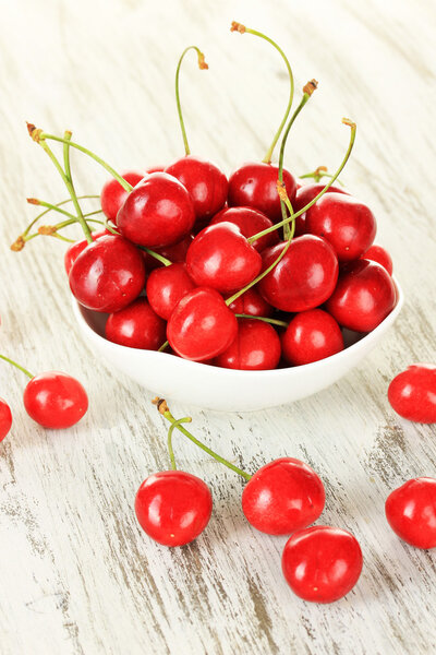 Cherry berries in bowl on wooden table close up