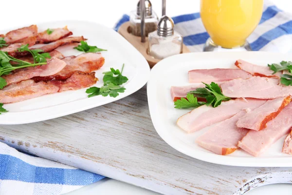 Bacon on plates on napkin on board isolated on white — Stock Photo, Image