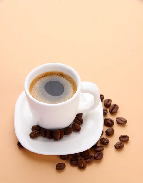 Cup of coffee with coffee beans on beige background — Φωτογραφία Αρχείου