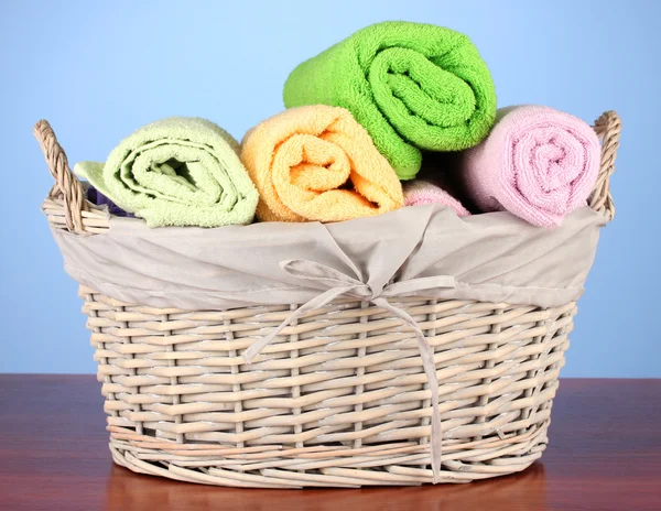 Kleurrijke handdoeken in mand op kleur achtergrond — Stockfoto