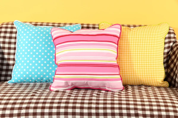 Almohadas de colores en el sofá sobre fondo amarillo — Foto de Stock