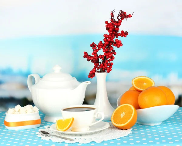 Beautiful white dinner service with oranges on blue tablecloth on natural background