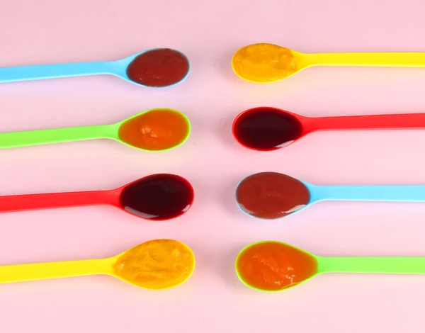 Baby puree in spoons on pink background — Stock Photo, Image