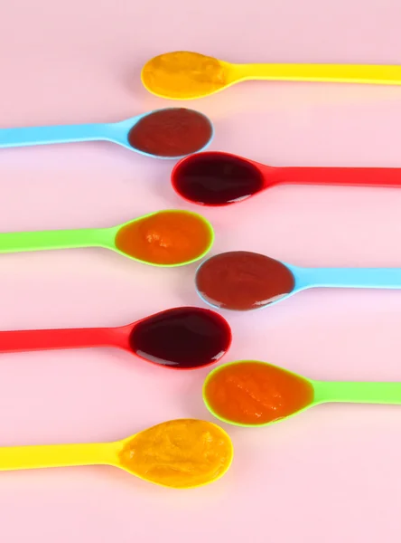 Baby puree in spoons on pink background — Stock Photo, Image