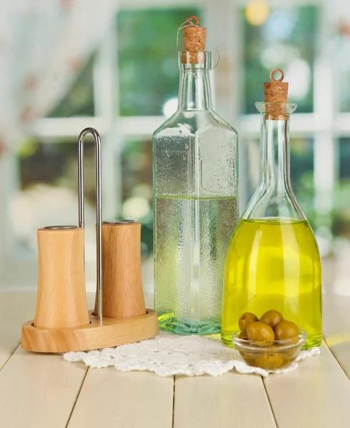 Original glass bottles with salad dressing on wooden table on window background — Stock Photo, Image