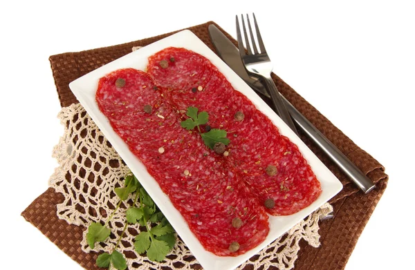 Sabroso salami en plato en servilleta aislado en blanco — Foto de Stock
