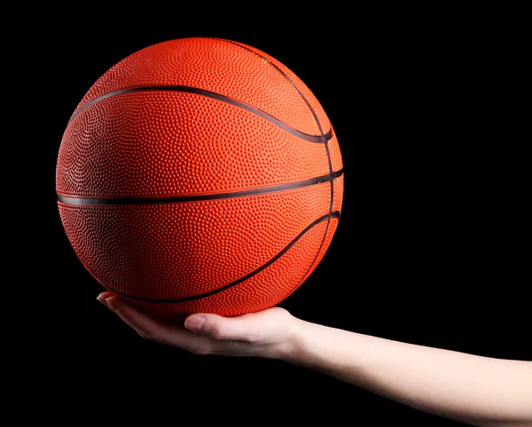 Basketball in woman hand on black background — Stock Photo, Image