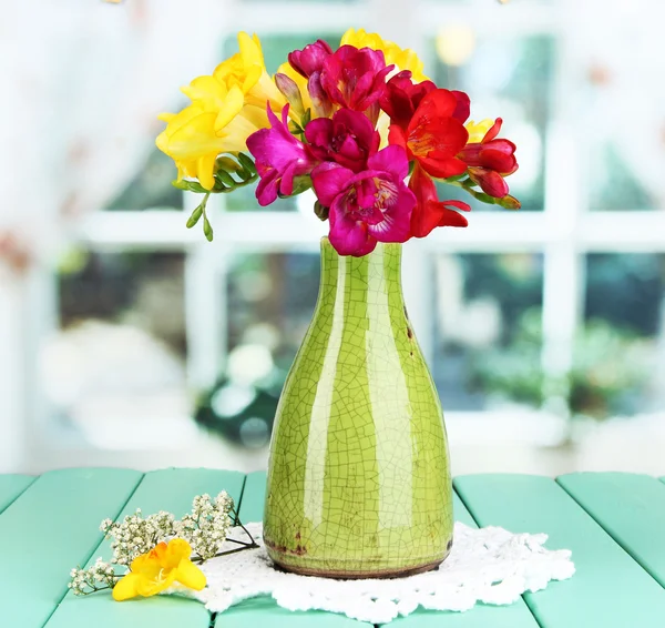 Schöner Strauß Freesien in blauer Vase auf Holztisch auf Fensterhintergrund — Stockfoto