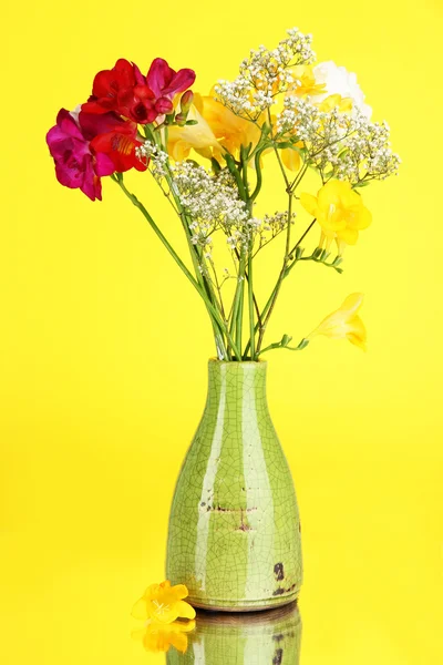 Hermoso ramo de freesia en jarrón sobre fondo amarillo — Foto de Stock