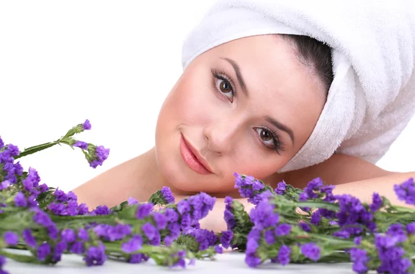 Mulher bonita com toalha na cabeça e flores isoladas em branco — Fotografia de Stock