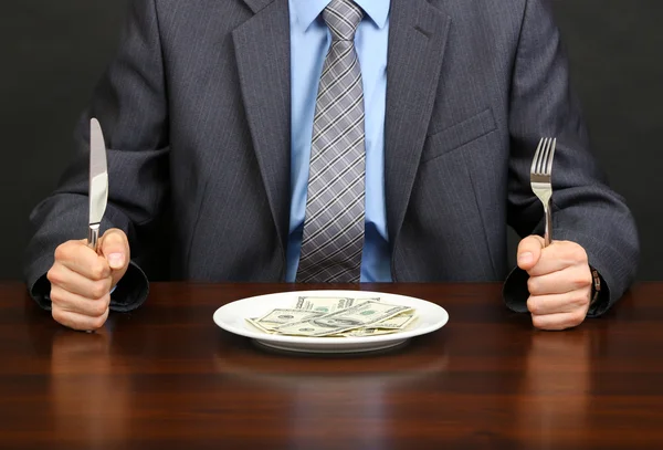 Joven empresario cenando dólares sobre fondo negro — Foto de Stock