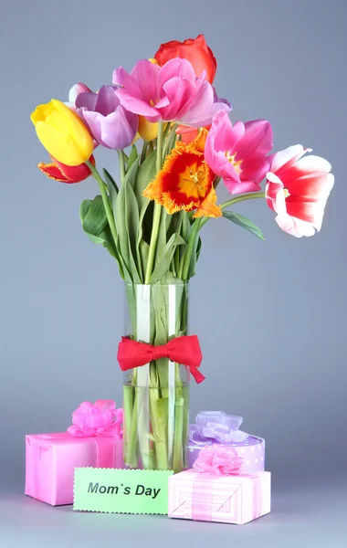 Beautiful tulips in bouquet with gifts and note on gray background — Stock Photo, Image