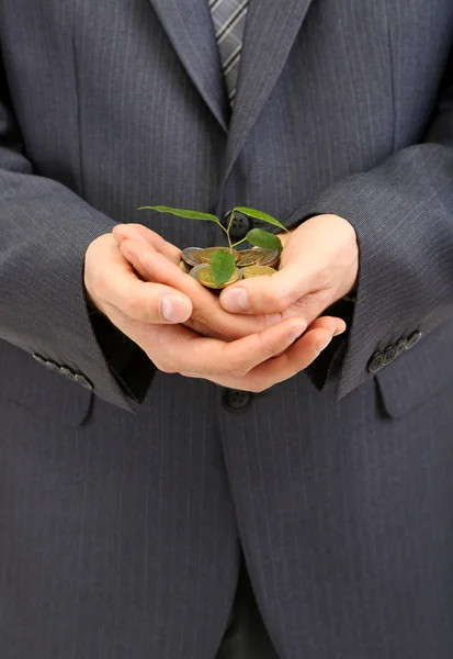 Jovem empresário com moedas e planta isolada no whit — Fotografia de Stock