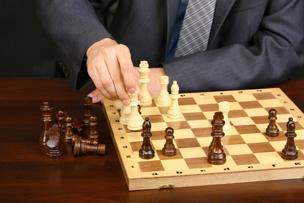 黒の背景にチェスをしている若いビジネスマン — ストック写真