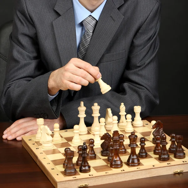 Joven hombre de negocios jugando ajedrez sobre fondo negro — Foto de Stock