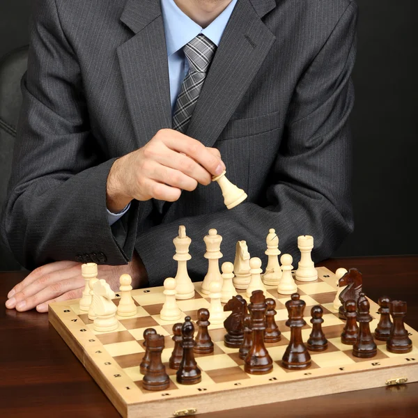 Junger Geschäftsmann spielt Schach auf schwarzem Hintergrund — Stockfoto